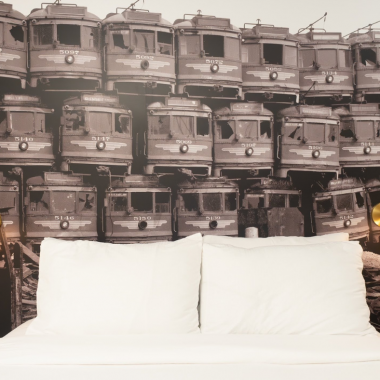 A wallpaper of red line buses frame a bed at The Redline Venice Hotel.